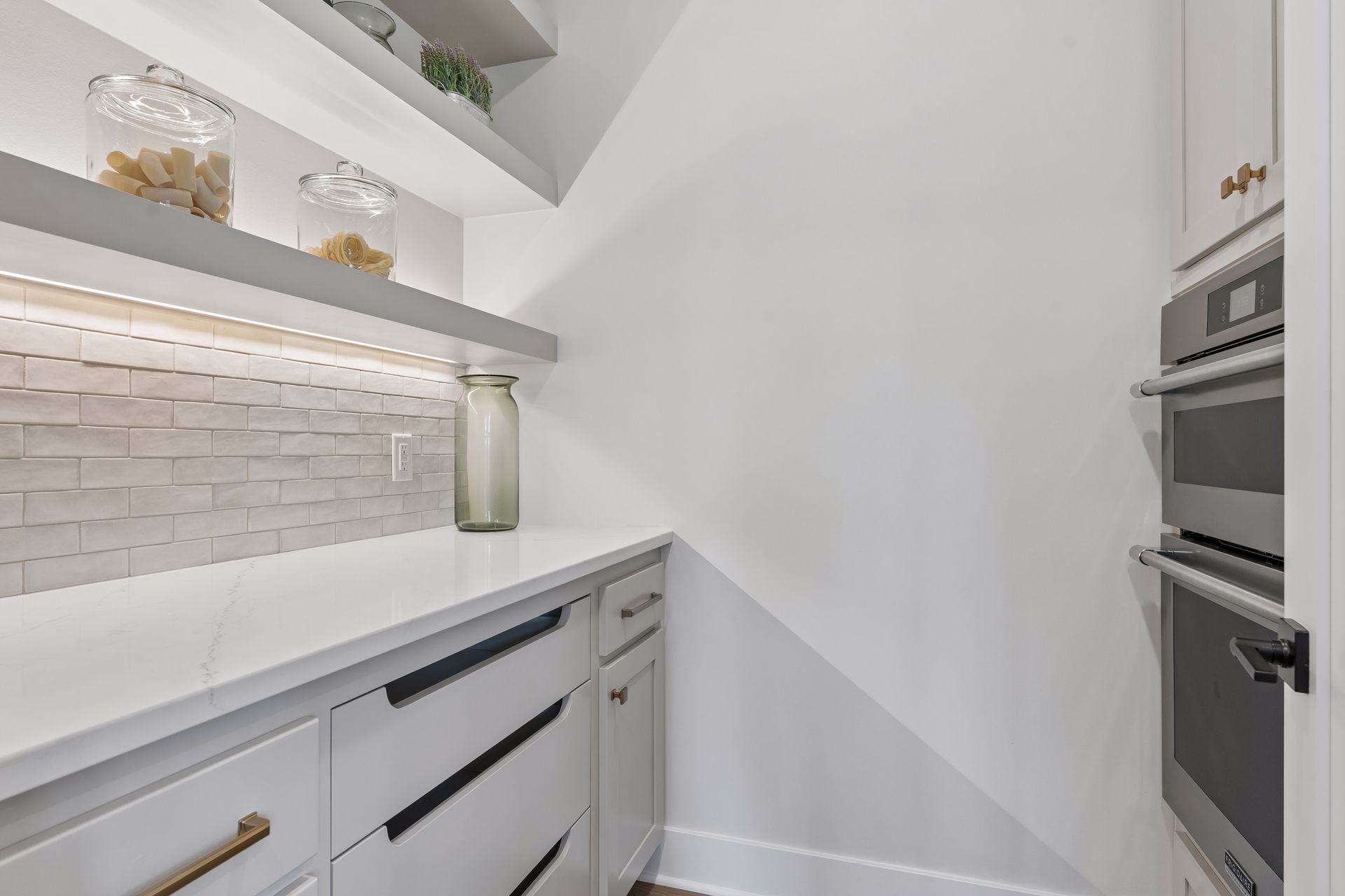 Walk-in pantry with custom cabinetry storage and built-in appliances
